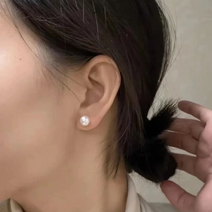 Close-up of a high-quality white natural freshwater pearl stud earring on model ear