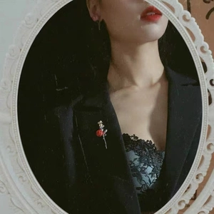 Detail einer roten Rosen-Vintage-Brosche am Revers eines schwarzen Blazers im Spiegel