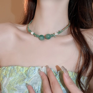 Dettaglio di una collana vintage di perline verdi con elementi di loto su una modella