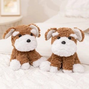 Plush Schnauzer dog toy in brown and white fur sitting on a soft white quilted bed