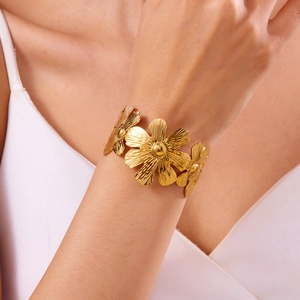 Close-up of golden daisy flower bracelet featuring brushed metal texture and petals