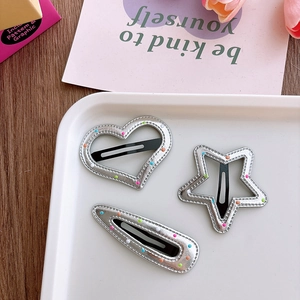 Detailed close-up of three silver-colored hollow hair clips in heart, star, and oval shapes