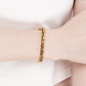 Detail of a minimalist gold irregular bamboo-shaped link bracelet worn on a wrist