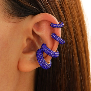 Close-up of four royal blue rhinestone C-shaped ear cuffs on a female model