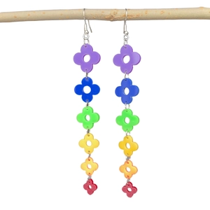 Detailed view of rainbow acrylic four-leaf clover tassel earrings on a natural branch
