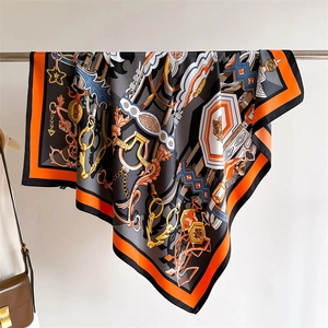 Macro detail of silk scarf featuring chain patterns and horsebit motifs in orange and grey