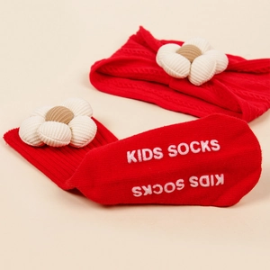 Détail de chaussettes en tricot rouge pour bébé avec fleurs et semelles antidérapantes