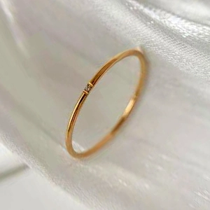 Macro detail of slim 18K gold plated steel ring with a single sparkling zircon stone