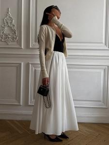Detail of high waist white A-line maxi skirt with pleated waist and flowy hem