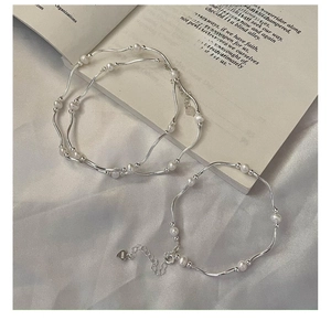 Detail of S925 sterling silver pearl bracelet on silk fabric with elegant metal curved bars