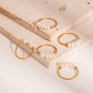 Fünferset elegante goldene Edelstahlringe mit echten Süßwasserperlen auf Steinuntergrund