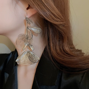 Detailed view of long multilayered metallic silver flower tassel earrings on model