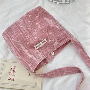 Dettaglio borsa a tracolla in velluto rosa con cuori bianchi e chiusura magnetica