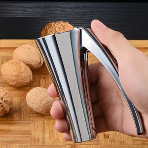 Manual garlic press and walnut cracker being held over walnuts on a wooden board