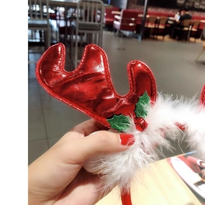 Close-up of a festive Christmas reindeer antler headband with red bells and white feathers