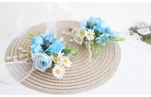 Détail de la boutonnière de mariage en soie bleue avec marguerite et ruban blanc