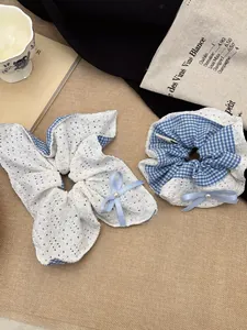 Detailed shot of blue plaid and white lace hair scrunchies with bows and pearls