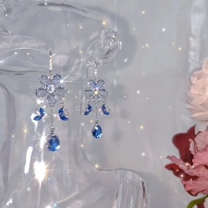 Macro detail of blue butterfly drop earrings with shimmering crystals and elegant tassels