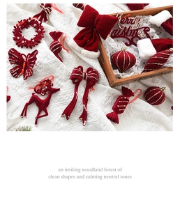 Detail of red velvet Christmas ornaments including bells and deer on white knit background