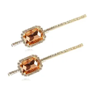 Close-up of amber crystal hair clips with champagne rhinestones on a gold metal base