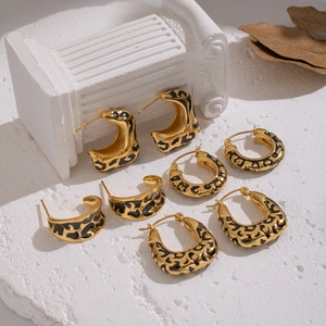 Leopard print gold hoop earrings in assorted geometric styles on a marble surface