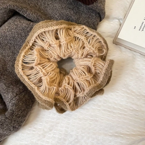 Close-up of camel knitted flower hair scrunchie with thick wool texture on white bedding