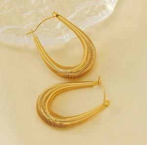Detailed macro view of gold U-shaped earrings featuring a sophisticated wire-wrapped texture