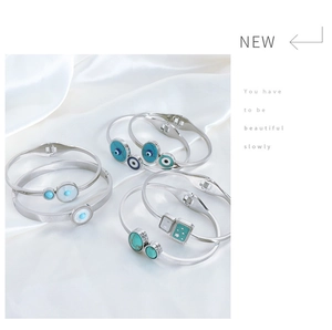 Detail of silver titanium steel bangles with blue evil eye and star charms on silk