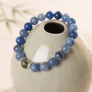 Macro shot of blue beaded bracelet with green charm and silver-toned textured spacers