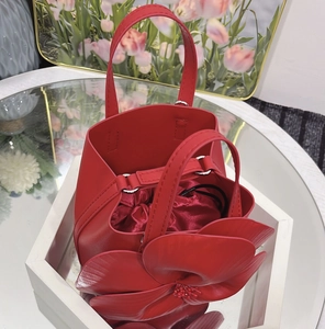 Detail of red petal tote bag showing 3D floral decoration and satin drawstring lining