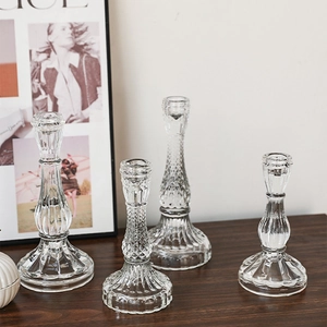 Set of four clear vertical ribbed glass candle holders on a dark wooden table