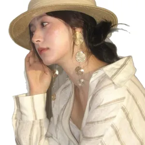Golden multi-layer wavy disc tassel earrings on female model with summer resort vibe