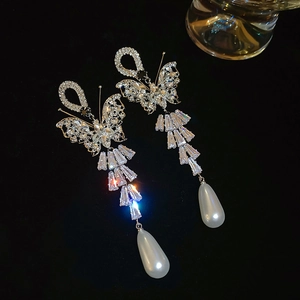 Detailed macro shot of tassel earrings featuring crystal butterflies and pearl drops