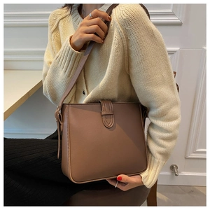 Brown bucket bag styled on shoulder with beige knit cardigan for casual look