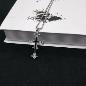 Hip hop silver cross necklace with black inlay and rhinestones on a white book