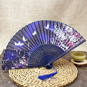 Detail of blue folding fan with white butterflies, pink cherry blossoms and silk tassel