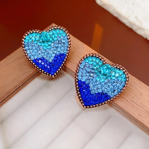 Macro shot of vintage heart earrings featuring a blue gradient of glittering crystals