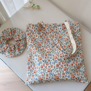 Close-up of floral cotton tote bag and matching scrunchie with warm orange flower patterns