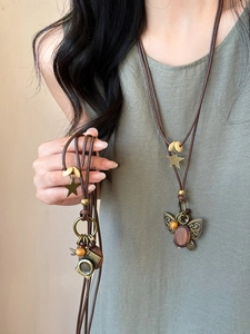 Close-up of vintage butterfly and camera pendants with wooden beads on brown cord necklace