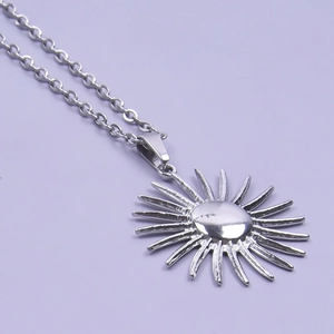 Close-up of a silver stainless steel sun pendant necklace with polished metal details