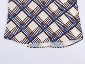 Detailed close-up of the curved hem on this brown and blue plaid long sleeve shirt