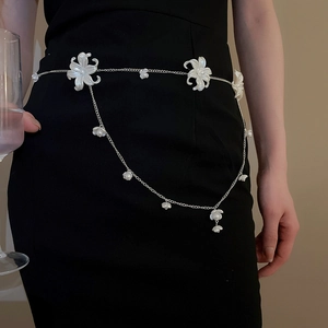 Detail of elegant white floral belt chain with silver metal links worn on a black dress