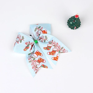 Close-up of a light blue Christmas bow hair tie with festive holiday prints