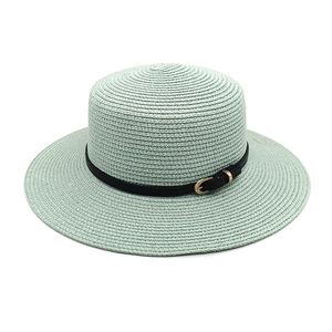 Detail of light green straw boater hat featuring fine texture and black leather band