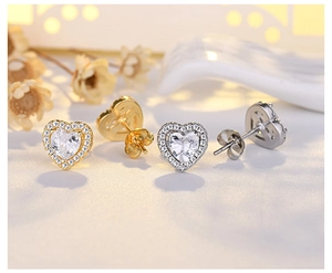 Close-up of gold and silver heart stud earrings with cubic zirconia pave setting
