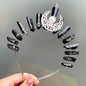 Macro detail of black crystal crown with silver crescent moon and pearl accents