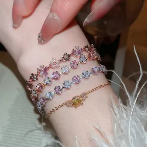 Elegant rose gold charm bracelets featuring zircon flowers and pearls on a woman's wrist