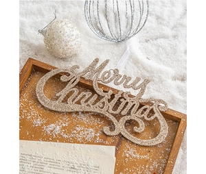 Close-up of golden glittery Merry Christmas lettering on snow with ornaments
