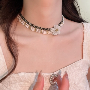 Detail of beaded floral choker with black and white beads and elegant gold spacers