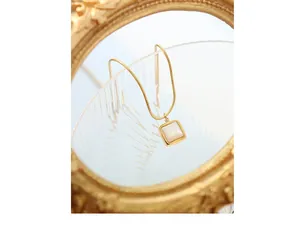 Gros plan d'un collier chaîne serpent dorée avec pendentif en nacre et cadre vintage